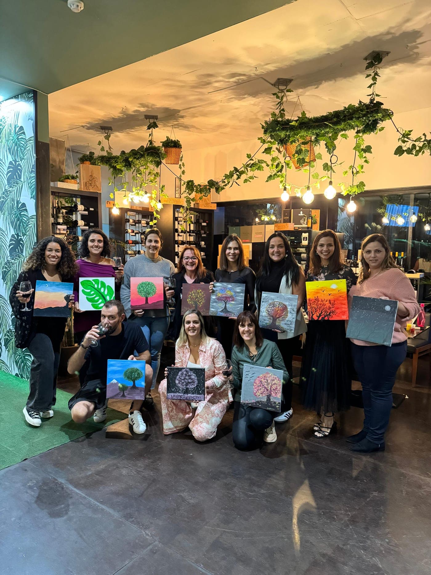 Group showing off their finished paintings at a Sip & Paint evening